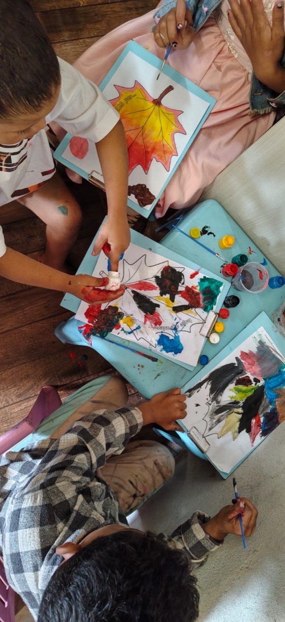 Crianças pintam juntas as folhas da atividade de evangelização infantil.