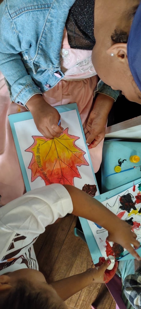 Crianças compartilham tintas durante a atividade sobre gratidão.