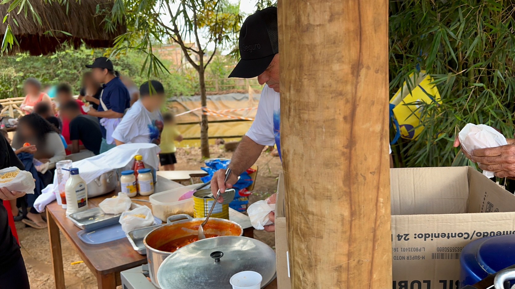 Tarefeiros e voluntários no preparo e na distribuição dos lanches. Rostos desfocados para preservar a identidade das crianças.